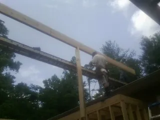 Carpenter setting a ridge beam over a new addition frame — Ice Dam Removal by Roofing Brothers in Chocowinity